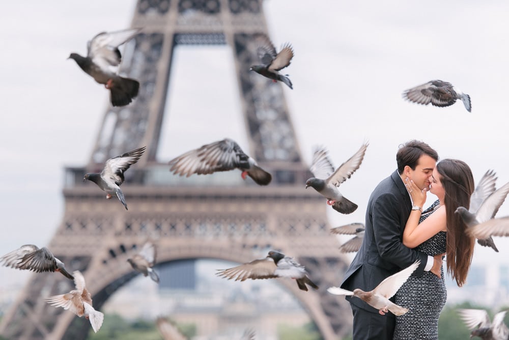 Paris engagement photographer capturing newly engaged couples kissing among flying birds at the Eiffel Tower Paris engagement photographer capturing newly engaged couples kissing among flying birds at the Eiffel Tower