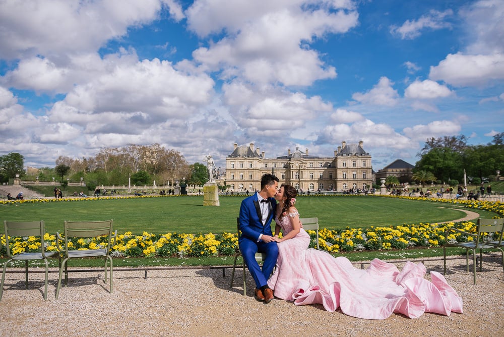 Blue sky, white clouds, Luxembourg gardens casstle and pre wedding couple with rich pink dress kissing Blue sky, white clouds, Luxembourg gardens casstle and pre wedding couple with rich pink dress kissing