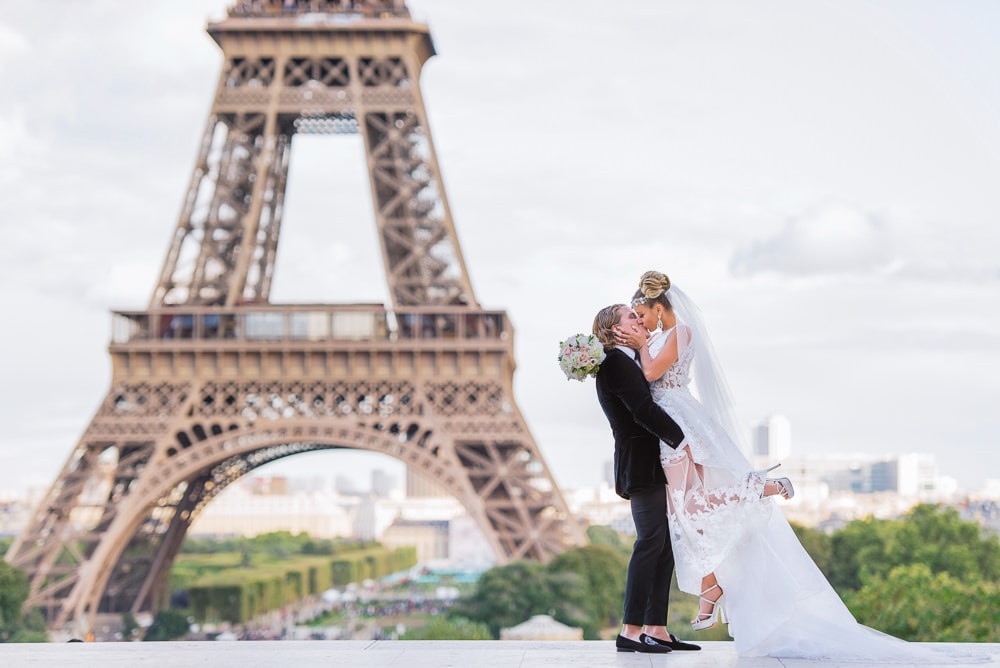 Bride kissing her groom while he is lifting her in the air in front of the Eiffel Tower Bride kissing her groom while he is lifting her in the air in front of the Eiffel Tower