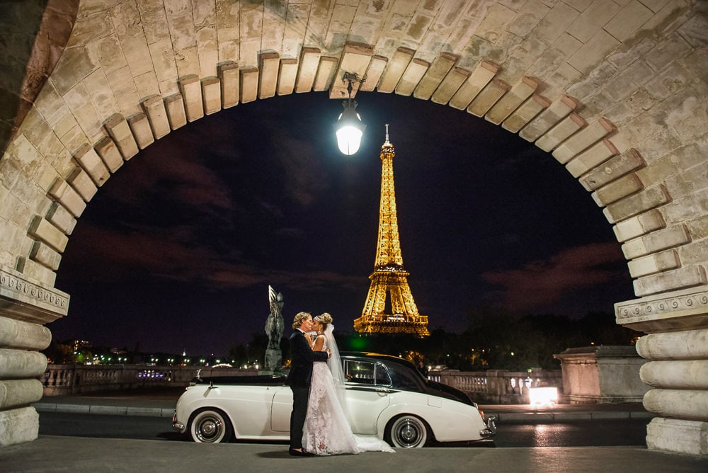 White Rolls Royce, the Eiffel Tower by night and a newly wed couple kissing passionately White Rolls Royce, the Eiffel Tower by night and a newly wed couple kissing passionately