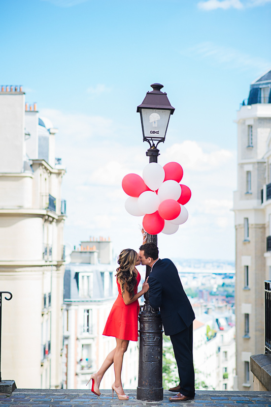 Couple kissing under red balloons in Montmarte