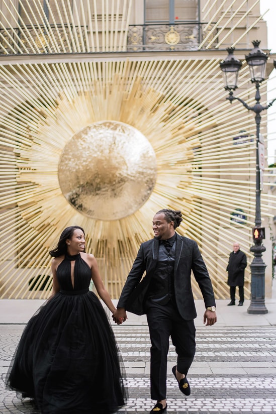 Couple photo shoot in Paris - Young couple running across the street in front of Louis Vuitton store in Place Vendome