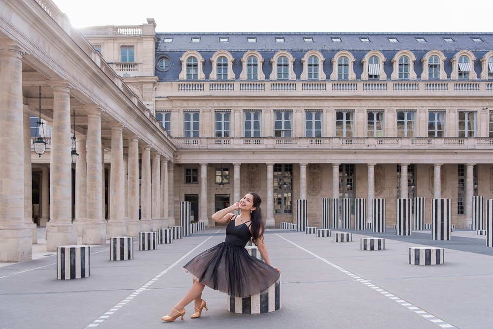 Woman in a black tulle dress posing among the striped Buren Columns at the Palais Royal in Paris
